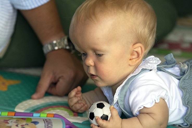 Photo of an infant with Achnodroplasia playing with a ball